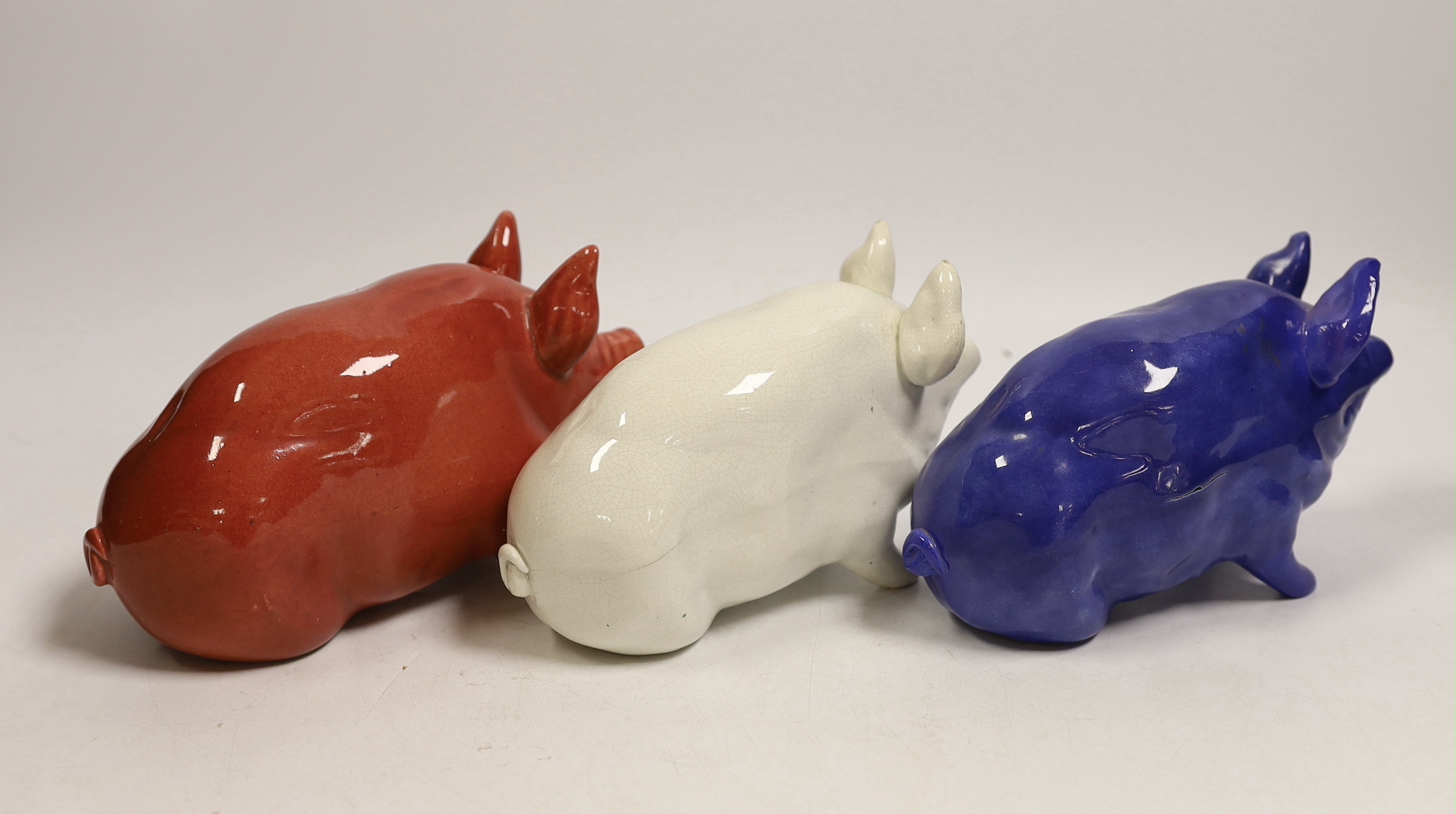 Three Wemyss ware pigs in cream, blue and pink glazes, 15cm